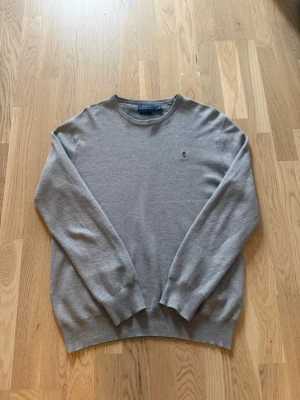 Grå  tröja från Polo Ralph Lauren - Säljer en grå polo ralph lauren tröja som inte används längre, har använts lite men är fortfarande i bra skick. Hör av dig vid frågor eller funderingar!