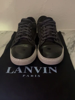 Svarta Lanvin sneakers i läder - Snygga svarta sneakers från Lanvin. Skorna är i uk 7 och sitter som eu 42. Skorna är i bra skick men sulkräm har används för att fräscha till de lite. Dustbag fås med 