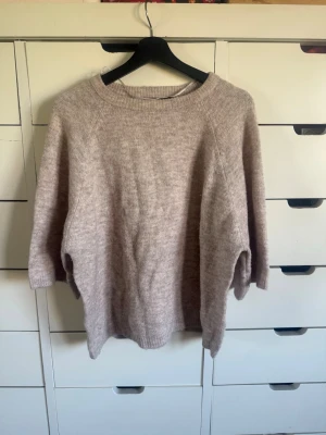 Beige stickad tröja från 157 - Mysig beige stickad tröja från 157 med rund halsringning och avslappnad passform. Tröjan har långa ärmar och ribbade muddar vid hals, ärmslut och nederkant. Perfekt för lager på lager under kyliga dagar.