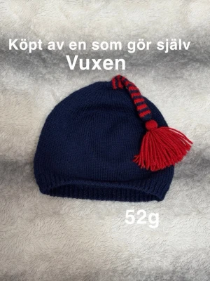 Mörkblå mössa med röd tofs - Stickad mörkblå mössa med röd och blårandig topp och stor röd tofs. Mössan är handgjord och passar vuxen. Perfekt för dig som vill ha en unik och färgglad accessoar till vintern.🌸 Köpt av en som gör själv. För vuxen. 