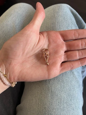Ballongformad berlock i guld och rosa - Söt liten berlock i form av en luftballong, gjord i rosé guldfärgad metall med rosa detalj i mitten. Perfekt att hänga på ett halsband eller armband för en unik och lekfull touch. Passar dig som gillar personliga smycken och vill sticka ut lite extra. Nypris 1200