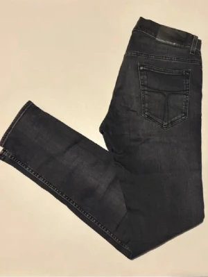 Tiger of Sweden jeans  - Snygga mörkblå jeans med rak passform och klassisk femficksdesign. Jeansen har diskreta sömmar och en patch bak i midjan. Perfekta för dig som gillar en enkel och stilren look.