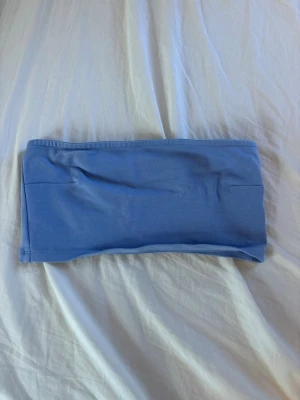 Ljusblå bandeau topp - Säljer en enkel och stilren ljusblå bandeau topp i mjukt stretchigt material. Toppen är axelbandslös och har en rak passform som sitter tajt mot kroppen.