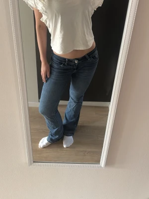Blå bootcut jeans med låg midja - Blå Lågmidjade utsvängda jeans från Nelly med stitch på fickorna. Knappt använda och i bra skick. 
