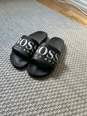 Svarta slides från Hugo Boss - Säljer ett par svarta tofflor från Hugo Boss i riktigt bra skick ✅ köpte för ca 700 säljer för 299 men priset går att diskuteras🔥