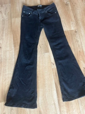 Low rise, bootcut, svarta jeans  - Säljer ett par svarta low waist jeans. Jeansen har en snygg retrovibe och passar perfekt för dig som gillar en unik stil. Materialet är mjukt och ger en skön känsla hela dagen. Säljer då den är lite för kort för mig 