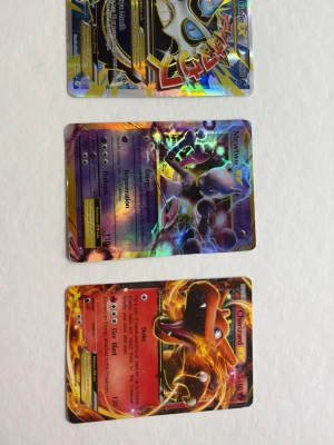 Pokémon EX samlarkort holografiska - Tre Pokémon EX samlarkort med holografisk yta: Mega Lucario EX, Mewtwo EX och Charizard EX. Korten har färgstarka illustrationer och glansig finish, perfekta för samlare eller Pokémon-fans. Alla korten är på engelska och har unika attacker och effekter.