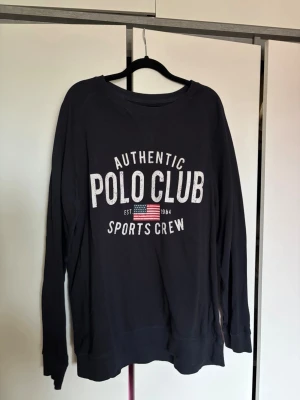 Mörkblå sweatshirt från Saint Vincent - Cool mörkblå sweatshirt från Saint Vincent med tryck 'Authentic Polo Club Sports Crew' och amerikansk flagga på bröstet. 