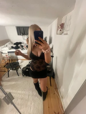 Svart spetsbody med blommönster - Säljer en svart body i genomskinlig spets med blommönster och djup urringning. Bodyn har tunna axelband och en feminin, figurnära passform. Perfekt för dig som vill ha något snyggt och trendigt under kläderna. Mer som en m