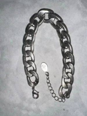 Tjockt silverfärgat kedjearmband - Säljer ett chunky armband i silverfärg med stora, platta länkar och minimalistisk låsning. Armbandet har även en förlängningskedja med en liten bricka. Perfekt för dig som gillar statement-smycken och vill ha något som syns. 