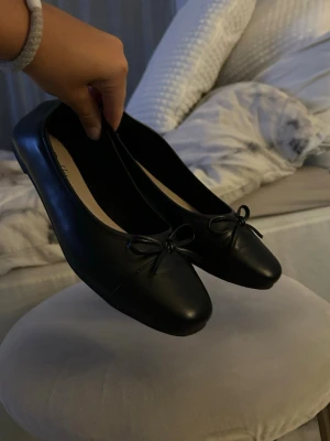 Svarta ballerinaskor från Duffy - Stilrena svarta ballerinaskor från Duffy med fyrkantig tå och dekorativ rosett framtill. Skorna är i ett slätt, glansigt material som ger en klassisk look. Perfekta att matcha till olika outfits och superbekväma att bära hela dagen. Använd endast 1 kväll så jättefint skick!🙏🏻pris 400kr kan diskuteras 💌💌