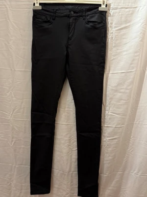 Svarta skinnjeans - Snygga svarta skinnbyxor med mid hög midja och klassisk femficksdesign. Jeansen har smal passform hela vägen ner och är perfekta till en avslappnad eller trendig look. Materialet ser stretchigt ut för extra komfort. Storlek M/L34