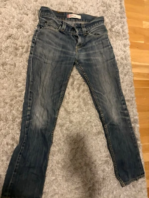 Levi's 511 Slim jeans blå - Ett par Levi's 511 från tidigt 2000 Slim jeans i klassisk blå denim med snygga slitningar och skön passform. Storleken är 30/34 men skulle säga att de är 29/32. Va inte rädda att höra av er!
