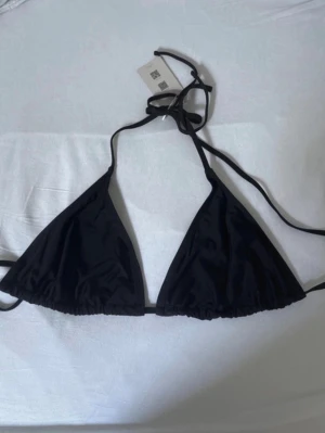 Svart trekantsbikini från Muséra - Stilren svart trekantsbikini från Muséra med tunna knytband i nacken och ryggen. Klassisk modell som ger en snygg siluett och passar perfekt till sommaren. 