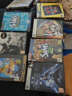 Samling PC-spel: Sims, Star Wars, Batman - Säljer en samling PC-spel med titlar som The Sims Unleashed, The Sims 2, Star Wars The Clone Wars, Star Wars The Force Unleashed, Batman Arkham Asylum, Battlefield 1942, Tony Hawk's Pro Skater 3 och The Simpsons Hit & Run. Fodral i plast, färgglada omslag och flera kända varumärken.
