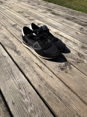 Svarta sneakers med vita detaljer - Philippe model skor, svarta och vita, storlek 43. Har använts ett fåtal gånger. Box tillkommer.  Priser är inte hugget i sten 
