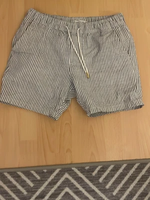 Randiga shorts från Les Noble Denmark - Säljer ett par snygga randiga shorts från Les Noble Denmark i vitt och blått. De har snörning i midjan och två sidofickor. Perfekta för både lite finare sammanhang men oxå om du bara vill vara lite extra stilig i vardagen