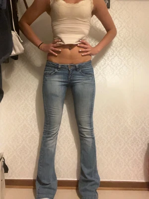 Ljusblå bootcut jeans från Only - Säljer ett par ljusblå bootcut jeans från Only med klassisk femficksmodell och snygga slitningar. Jeansen har normal midja, knappgylf och lätt utsvängda ben. Perfekta till en trendig och avslappnad look.