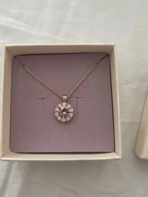 Lily and Rose halsband med rosa pärlor - Snyggt halsband från Lily and Rose med guldfärgad kedja och ett runt hänge dekorerat med ljusrosa och rosa pärlor i blomliknande mönster. Perfekt accessoar för dig som gillar feminina detaljer och pastellfärger.