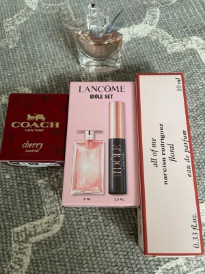 Parfym-minisar med Lancome, Coach & Narciso - Ett parfymset med tre olika dofter: Lancome Idôle i rosa flaska, Coach Cherry i röd ask och Narciso Rodriguez All of Me i vit och rosa förpackning. Setet innehåller både miniflaskor och en mascara. Perfekt för dig som vill testa flera lyxiga dofter.