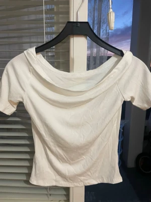 Vit ribbad topp med bred krage - Säljer en vit ribbad topp med bred, snygg krage och korta ärmar. Toppen har en figurnära passform. Tror den är från gina tricot. 