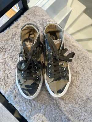 Millitär sneakers från Urban Classics - Snygga höga sneakers från Urban Classics i militär mönster. Perfekt till hösten som nu kommer. Säljer pga att dem inte passar mig.