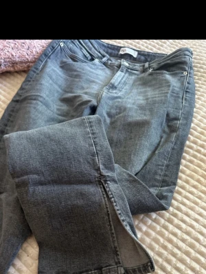 Grå raka jeans med hög midja - Säljer ett par grå jeans med rak passform och hög midja. Klassisk femficksmodell med bälteshällor och dragkedja. Jeansen har en snygg tvättad look och är tillverkade i denim. Perfekta till en avslappnad stil.