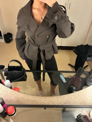 Kort mörkbrun trenchcoat med bälte - Säljer min nya trench coat från bershka. Kommer inte till nån använding då jag bara använt den 1 gånf