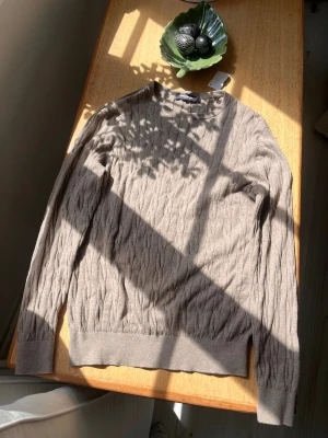 Beige kabelstickad tröja Dressmann - Säljer en beige kabelstickad tröja från Dressmann i storlek S. Tröjan har rund halsringning, långa ärmar och ribbade muddar vid ärmslut och nederkant. Perfekt för dig som gillar en klassisk och stilren look.