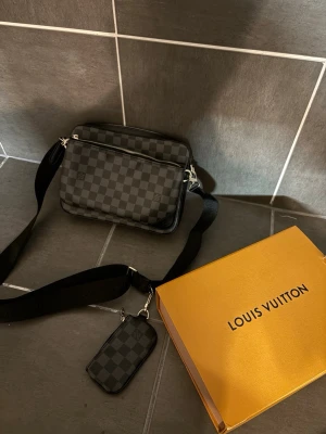 Axelväska grå och svart - Säljer en väldigt fin axelväska som är i färgen grå och svart, den är i fint skick och dustbag, kvitto och förpackning medföljer