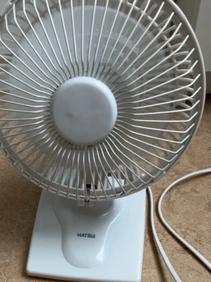 Vit bordsfläkt från Matsui - Säljer en vit bordsfläkt från Matsui med rund form och skyddsgaller i plast. Fläkten har en enkel design och står på en stabil fot. Perfekt för att svalka sig under varma dagar. Strömkabel medföljer.