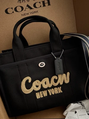Coach väska - Coach cargo tote, helt ny. Medföljer långt band 💛