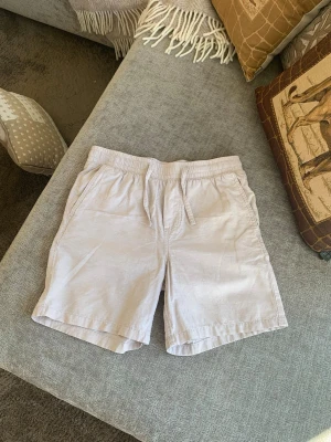Beige shorts med snörning XS - Säljer ett par ljusbeige shorts i storlek XS. De har elastisk midja med snörning och två sidofickor. Perfekta för varma sommardagar och tillverkade i ett mjukt bomullsliknande material. Enkla att matcha med det mesta och riktigt sköna att bära.