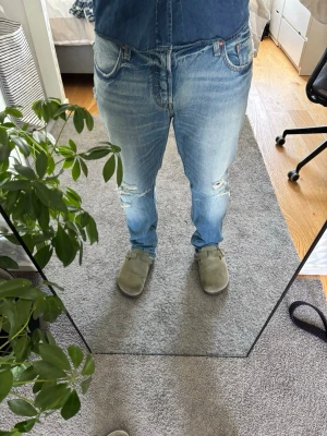 Levi's ljusblå vintage jeans - Säljer ett par klassiska ljusblå Levi's jeans med vintagekänsla. Jeansen har raka ben, fem fickor och den ikoniska röda Levi's-lappen på bakfickan. Materialet är slitstark denim i 100% bomull och passformen är relaxed fit. Storlek 31:32 