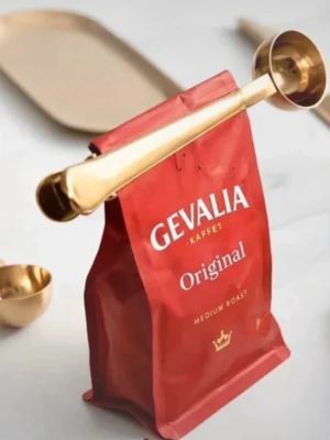 Guldfärgad kaffemått med klämma - Snygg och praktisk kaffemått i metall med guldfinish. Måttet har en rundad skopa och ett handtag som även fungerar som klämma för att försluta kaffepåsar. Perfekt till köket för att hålla kaffet fräscht och dosera rätt mängd.