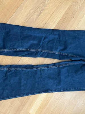 Mörkblå raka jeans från Monki - Säljer ett par mörkblå jeans från Monki i rak modell. Klassisk femficksdesign med gul kontrastsöm och knappstängning. Jeansen är tillverkade i denim och har en tidlös look som passar till det mesta.