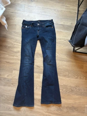 True religon - Marinblåa true religon jeans i modell joey storlek W26. Säljer pågrund av att jag köpte fel storlek. Använda några gånger så dom har pyttelite slitningar längds ner (se bild) men annars bra kvalite. Buda gärna och ställ frågor så svarar jag så fort jag kan