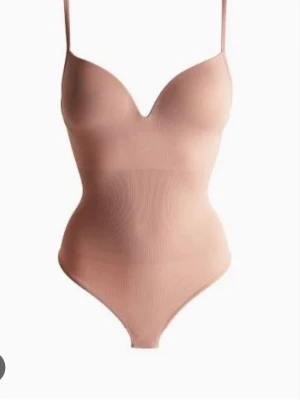 Populära bodyn - Säljer en nude-färgad body med tunna axelband och vadderade kupor. 