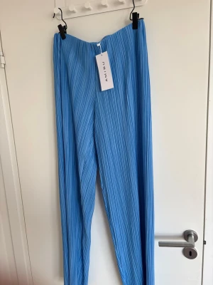 Blå plisserade leggings från Amisu - Snygga blå leggings från Amisu med plisserad struktur och hög midja. Tillverkade i ett mjukt och stretchigt material som ger en bekväm passform. Perfekta för dig som vill ha en trendig och avslappnad look.