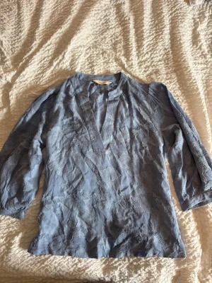 Blå blommig blus med trekvartsärm - Snygg blå blus med blommigt mönster och trekvartsärmar. Blusen har en v-ringad hals och är gjord i ett tunt, lätt material med struktur. Perfekt att styla med jeans eller kjol för en trendig look. Kostar 1299 kr ny!💓