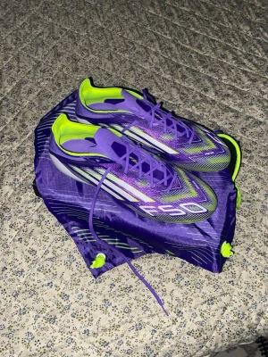 Adidas F50 Elite  - Säljer ett par riktigt snygga Adidas F50 Elite i färgen lila, gul och grön. Helt nya aldrig använda. Storlek 42. Köpte dem för 2399kr. Säljer dem för 999kr, kom med bud!!