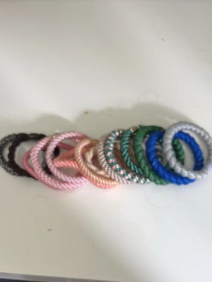 Färgglada  hårsnoddar - Säljer ett set med  hårsnoddar i olika färger som rosa, blå, grön, silver, svart och beige. De är gjorda av elastiskt material med glansig yta och passar perfekt för att hålla håret på plats utan att slita. Perfekt accessoar för att addera färg till din look.