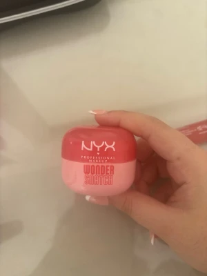NYX Wonder Snatch läppbalsam rosa/röd - NYX Professional Makeup Wonder Snatch läppbalsam i en rund burk med tvådelad design i rött och ljusrosa. Perfekt för att återfukta läpparna och ge dem en fräsch look. Snygg och praktisk för väskan. den har använt några gånger. Det finns mer än 80 % av produkten kvar.