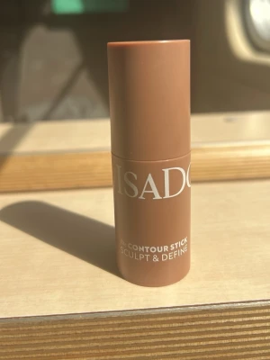 IsaDora Contour Stick Dark Almond - IsaDora Contour Stick i färgen 34 Dark Almond. En krämig bronzer i stickformat som är enkel att applicera och blenda ut. Perfekt för att skulptera och definiera ansiktet. Kommer i en smidig brun plastförpackning med vit text.