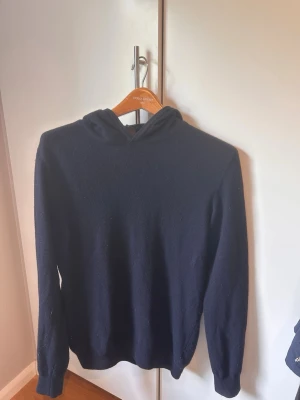 Mörkblå cashmerehoodie från Oscar Jacobson - Säljer en stilren mörkblå cashmerehoodie från Oscar Jacobson.  Hoodien är i ett mjukt och skönt material, perfekt för en avslappnad look. Passar dig mellan 170-180