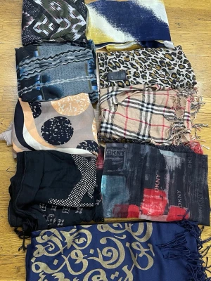 Mix av mönstrade sjalar i olika färger - Säljer ett paket med flera sjalar i olika färger och mönster, bland annat leopard, rutigt, grafiskt och abstrakt. Färgerna varierar från blått, svart, beige, rött till guld och fler. Perfekt för dig som vill variera din stil med unika accessoarer.från 100kr styck eller räkna ett paketpris 