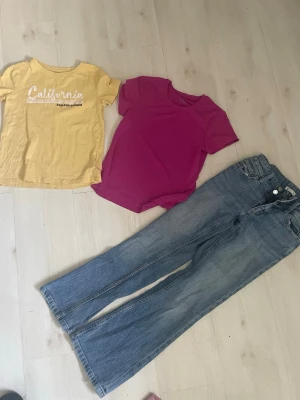 Blå raka jeans med hög midja+2 T-shirts  - Säljer ett par klassiska blå jeans med rak passform och hög midja. Jeansen har fem fickor, bälteshällor och stängs med knapp och dragkedja. Perfekta till en avslappnad och trendig look.Två T-shirt i storlek 134-140 stora i storlek 