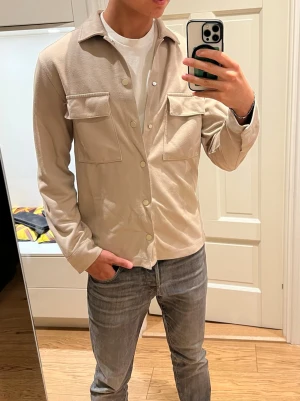 Beige overshirt med fickor - Säljer denna stilrena beigea overshirt med två stora bröstfickor och knappar framtill. Den är köpt på hm men tillverkas inte längre. Storlek S. Inga tecken på användning. Skriv om du undrar något✌️