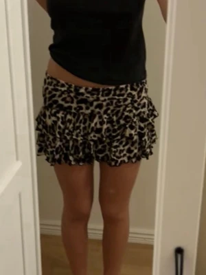 Leopardmönstrad volangkjol - Kort kjol med leopardmönster och flera volanger. Kjolen har en bred midja och är sydd i ett lätt, fladdrigt material som ger en cool och trendig look. Perfekt för dig som vill sticka ut med ett djuriskt print. Bara testad så den är ny. Storleken på lappen är M men jag skulle säga att det är storlek S då det är min storlek och den sitter bra, men den är också väldigt stretchig så den sitter även bra på M.
