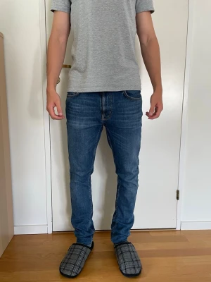 Nudie Lean Dean - Snygga blå slim fit jeans från Nudie modell Lean Dean. Köpta på Nudie butiken i Stockholm och är sparsamt använda, nyskick. Personen på bilden är 181 cm och väger 70 kg. Säljs för 300kr, hör av er vid frågor!